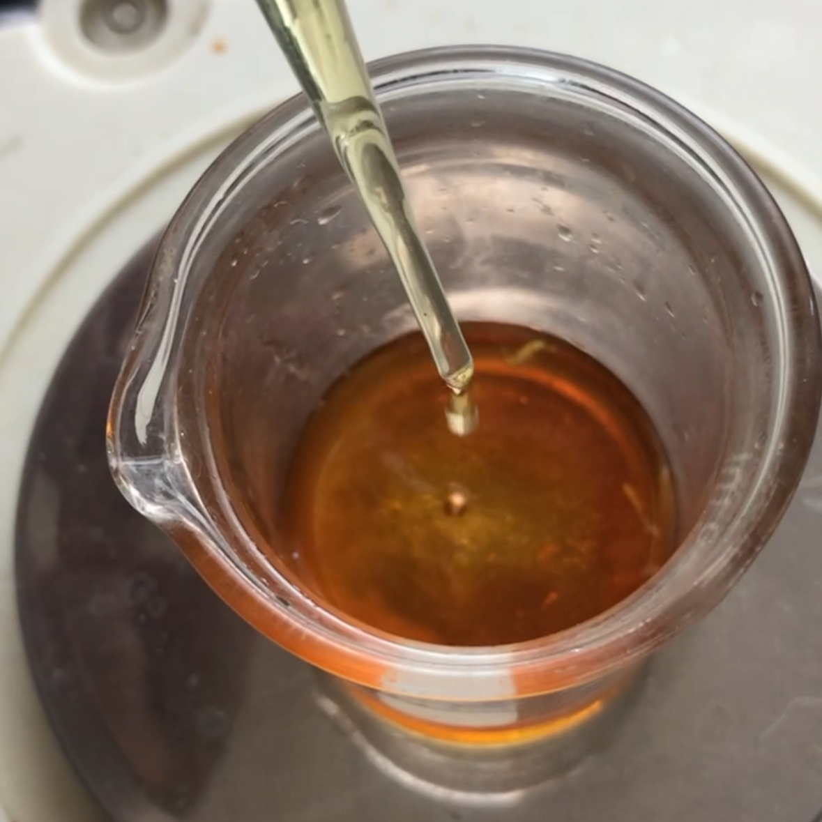 Glass container with essential oil patchouli being dripped into it using a dropper.